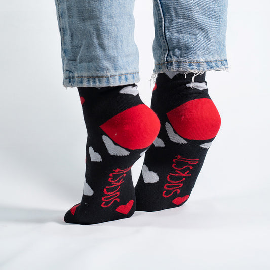 Unisex black socks with white and red hearts, perfect for Valentine’s Day or romantic occasions.
