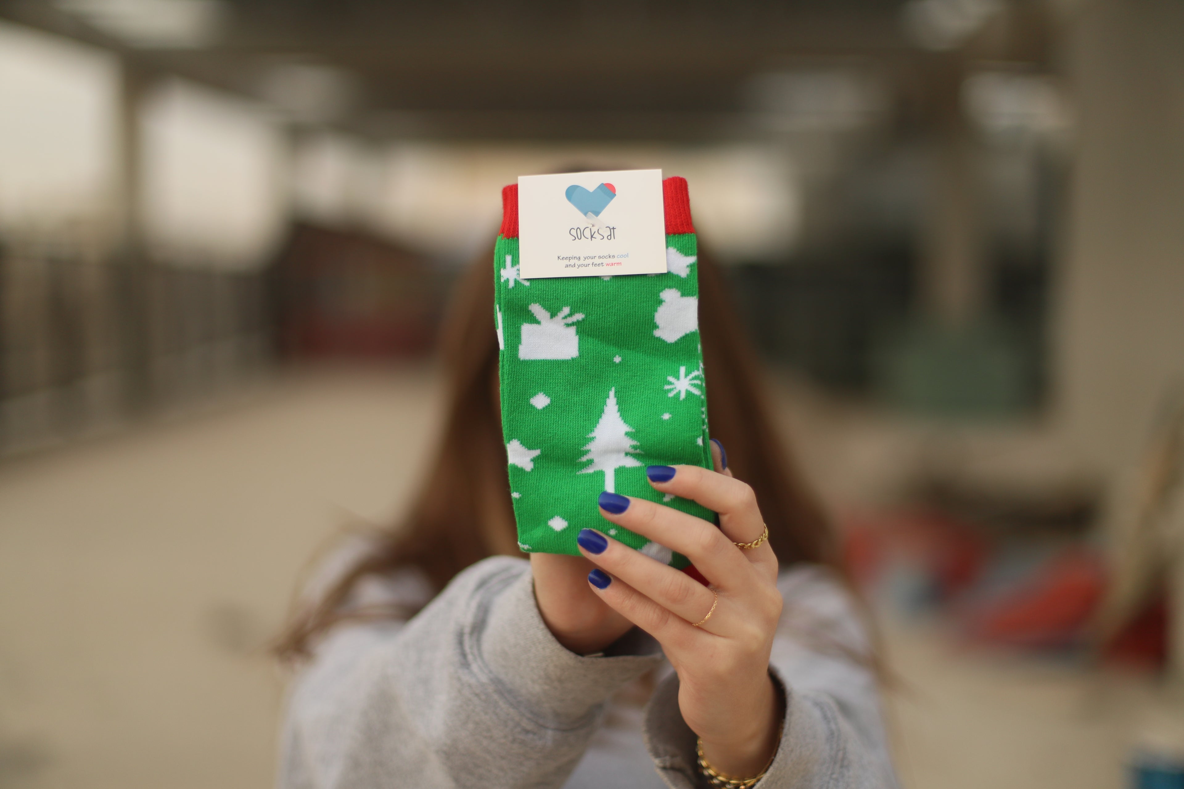 Person holding a green sock with Christmas patterns in an indoor setting